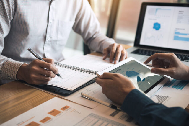Bookkeeper and client discuss finances with the help of notes and graphs at a table.