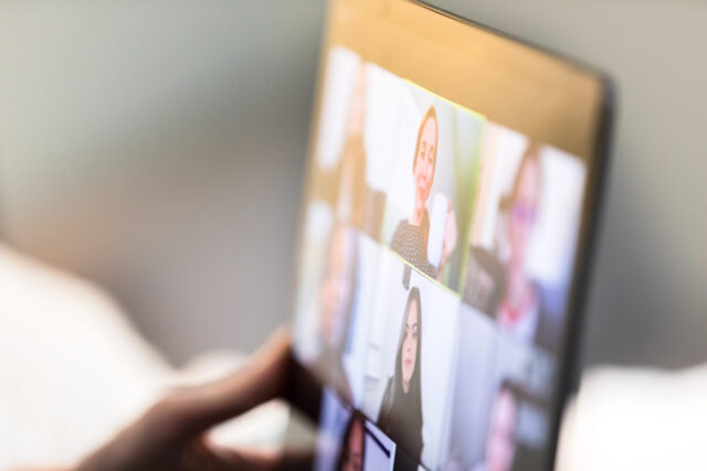 A laptop shows a video call with overseas employees