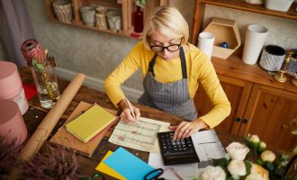 Female sits at her kitchen table working out numbers for her self-employed business
