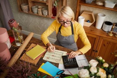 Female sits at her kitchen table working out numbers for her self-employed business