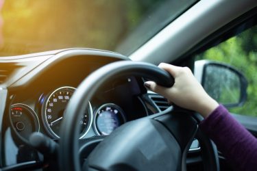 An employee holds the steering wheel as they drive a company car